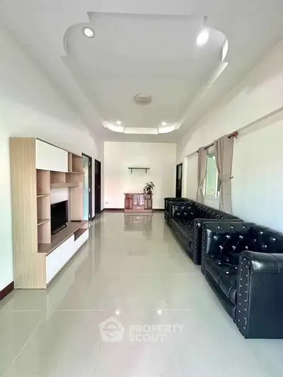 Spacious living room with modern leather sofas and sleek entertainment unit, perfect for relaxation and entertainment.