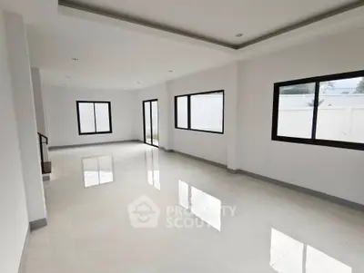 Spacious modern living room with large windows and sleek tile flooring.