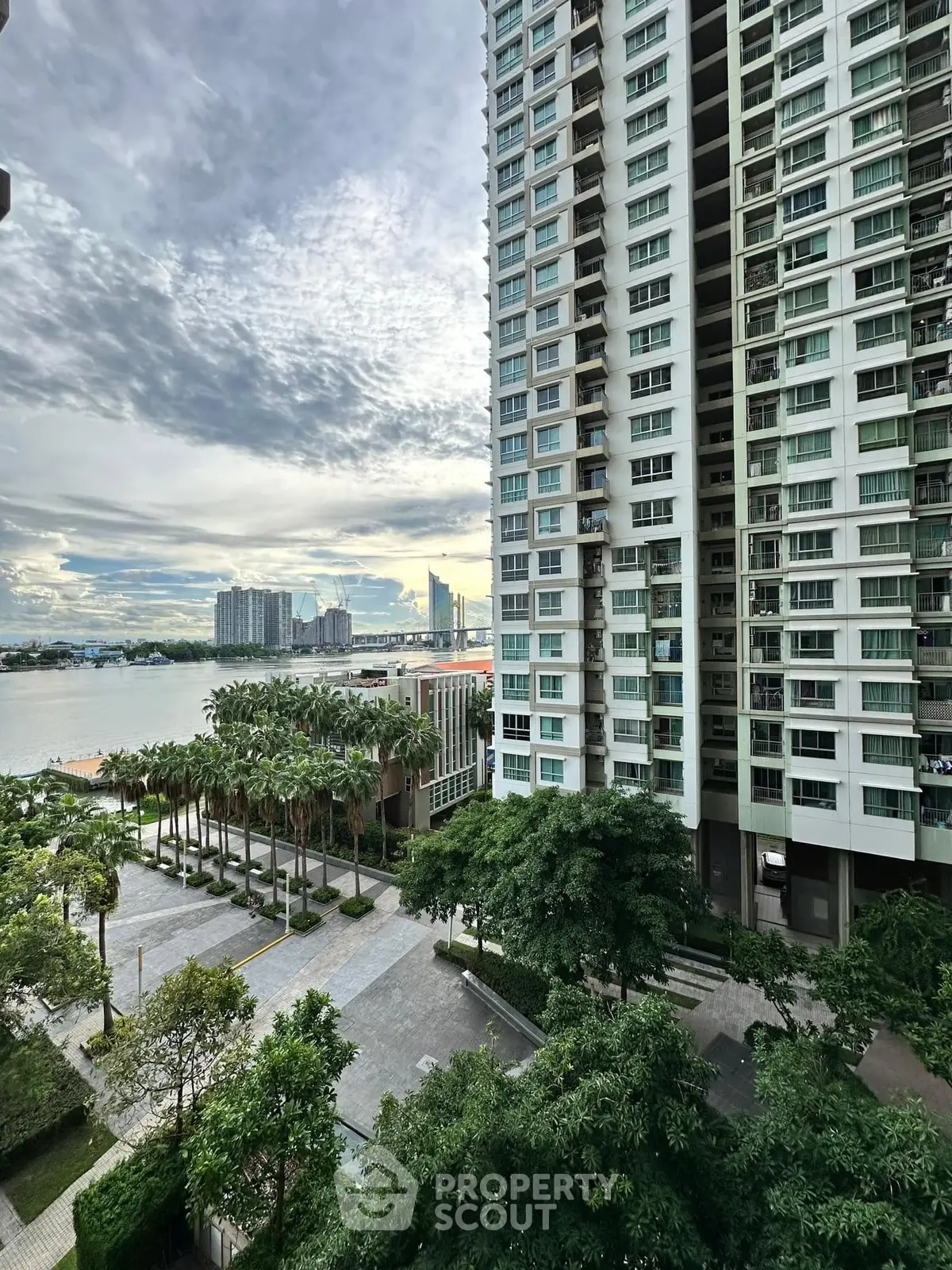 Stunning high-rise building with river view and lush greenery in urban setting.