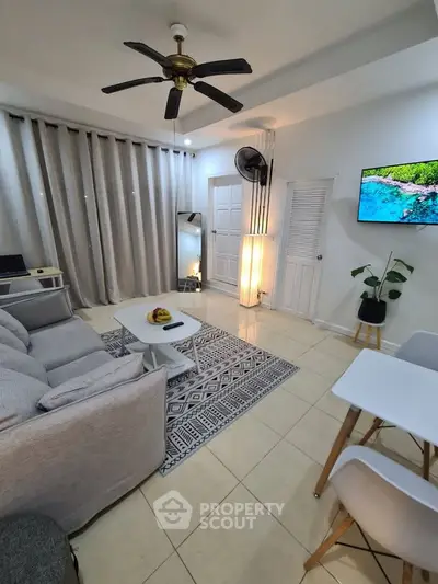 Modern living room with stylish decor, ceiling fan, and wall-mounted TV, perfect for relaxation.