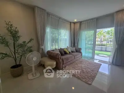 Spacious living room with elegant decor and large windows offering garden views.