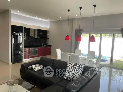 Modern open-plan living room with sleek kitchen and pool view, featuring stylish decor and ample natural light.