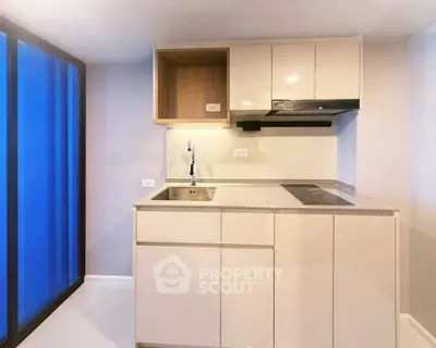 Modern kitchen with sleek cabinetry and electric stove in a compact layout.