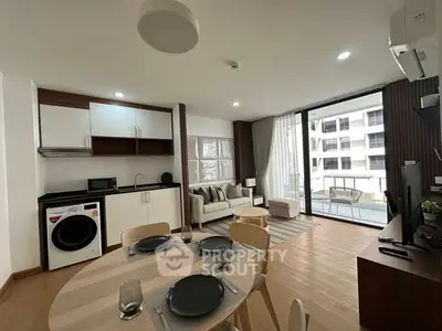Modern open-plan living room with kitchen and balcony view in a stylish apartment.