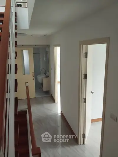 Modern hallway with wooden staircase and bathroom entrance in a contemporary home.