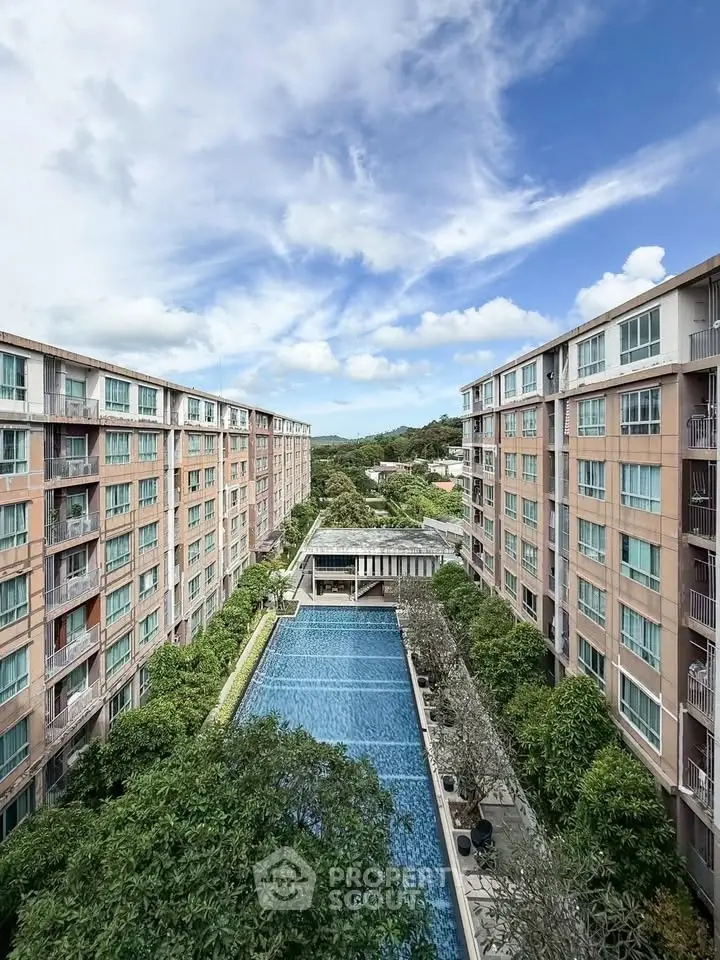 Stunning aerial view of modern apartment complex with central swimming pool and lush greenery.