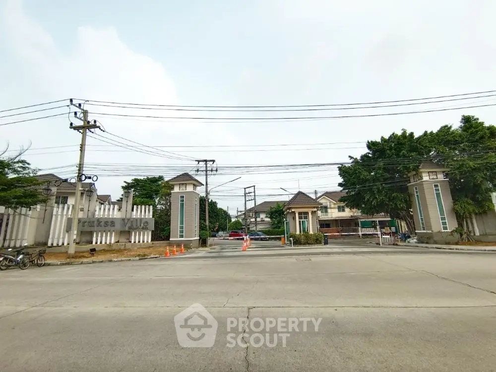Charming gated community entrance with lush greenery and modern architecture.