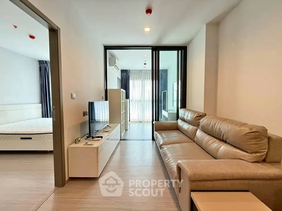 Modern apartment living room with leather sofa and open view to bedroom
