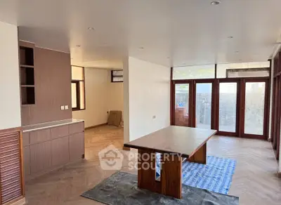 Spacious open-plan living area with wooden flooring and large windows for natural light.