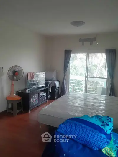 Spacious bedroom with large window and balcony access, featuring hardwood floors and modern furnishings.