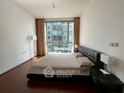 Spacious modern bedroom with large window and city view in luxury apartment.