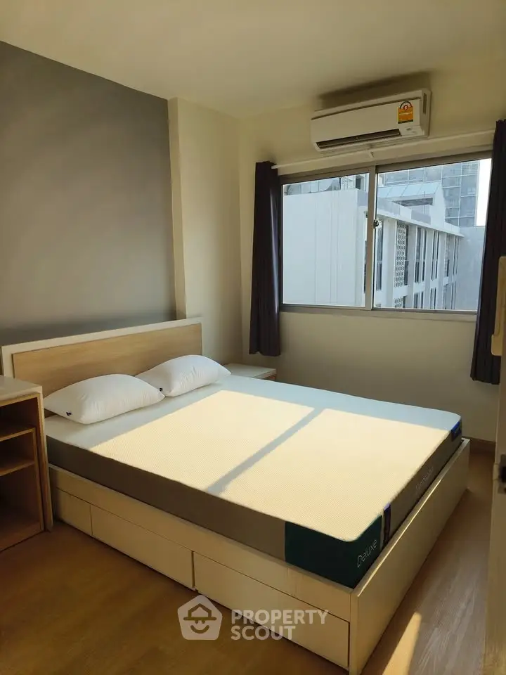 Bright and cozy bedroom with modern furnishings and large window offering city views.