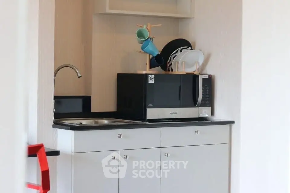 Compact kitchen area with microwave and sink, ideal for small apartments or studios.