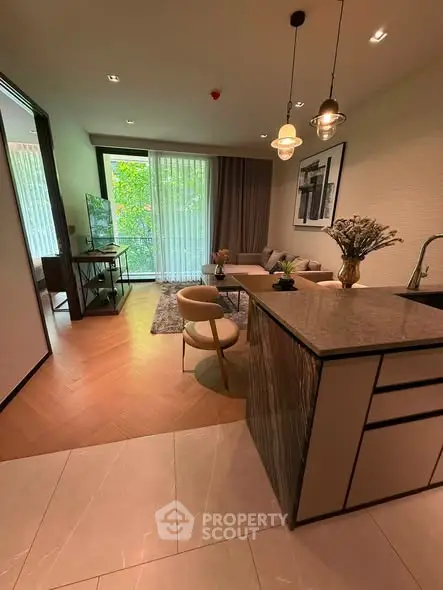 Modern open-layout living room with stylish decor and large windows offering lush green views.