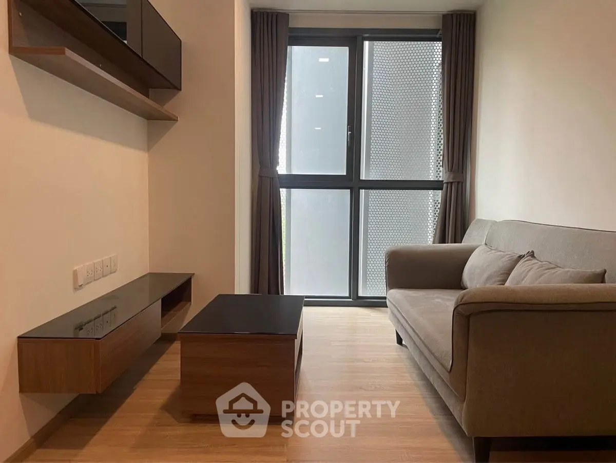 Modern living room with sleek furniture and large window, perfect for urban living.