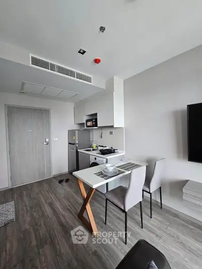 Modern compact kitchen and dining area with sleek design and wooden flooring.