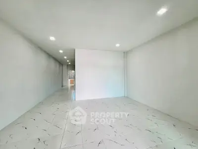 Spacious empty room with modern tiled flooring and recessed lighting, ideal for customization.