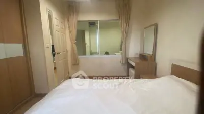 Cozy bedroom with wooden furniture and large window for natural light.