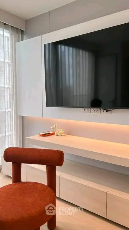 Modern living room with sleek TV setup and stylish red chair, perfect for contemporary urban living.