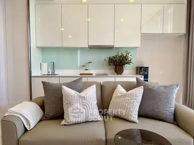 Modern living room with sleek kitchen backdrop and stylish decor