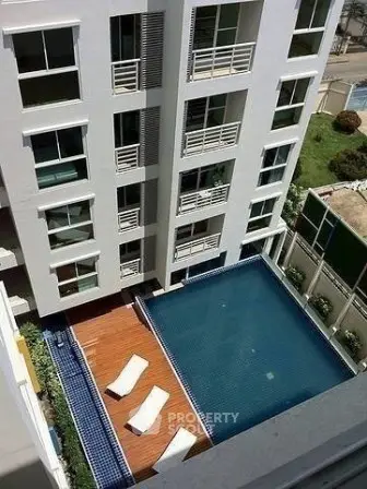 Modern apartment building with a luxurious rooftop pool and sun loungers.