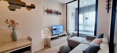 Modern living room with stylish decor and cozy seating area, featuring a TV and large window for natural light.