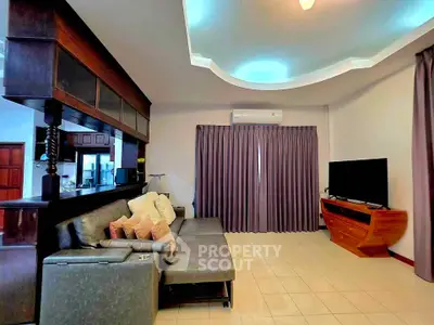 Spacious living room with modern decor and large TV, perfect for relaxation.