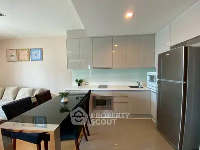 Modern kitchen with sleek cabinetry and dining area in open layout apartment.