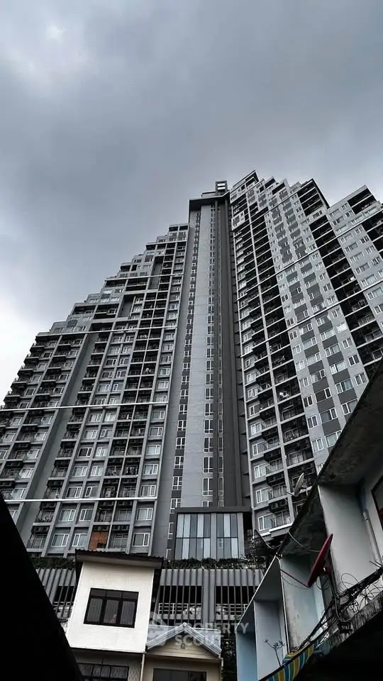 Stunning high-rise building with modern architecture under a cloudy sky, showcasing urban living at its finest.