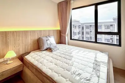 Cozy bedroom with modern decor and large window offering a city view, perfect for urban living.