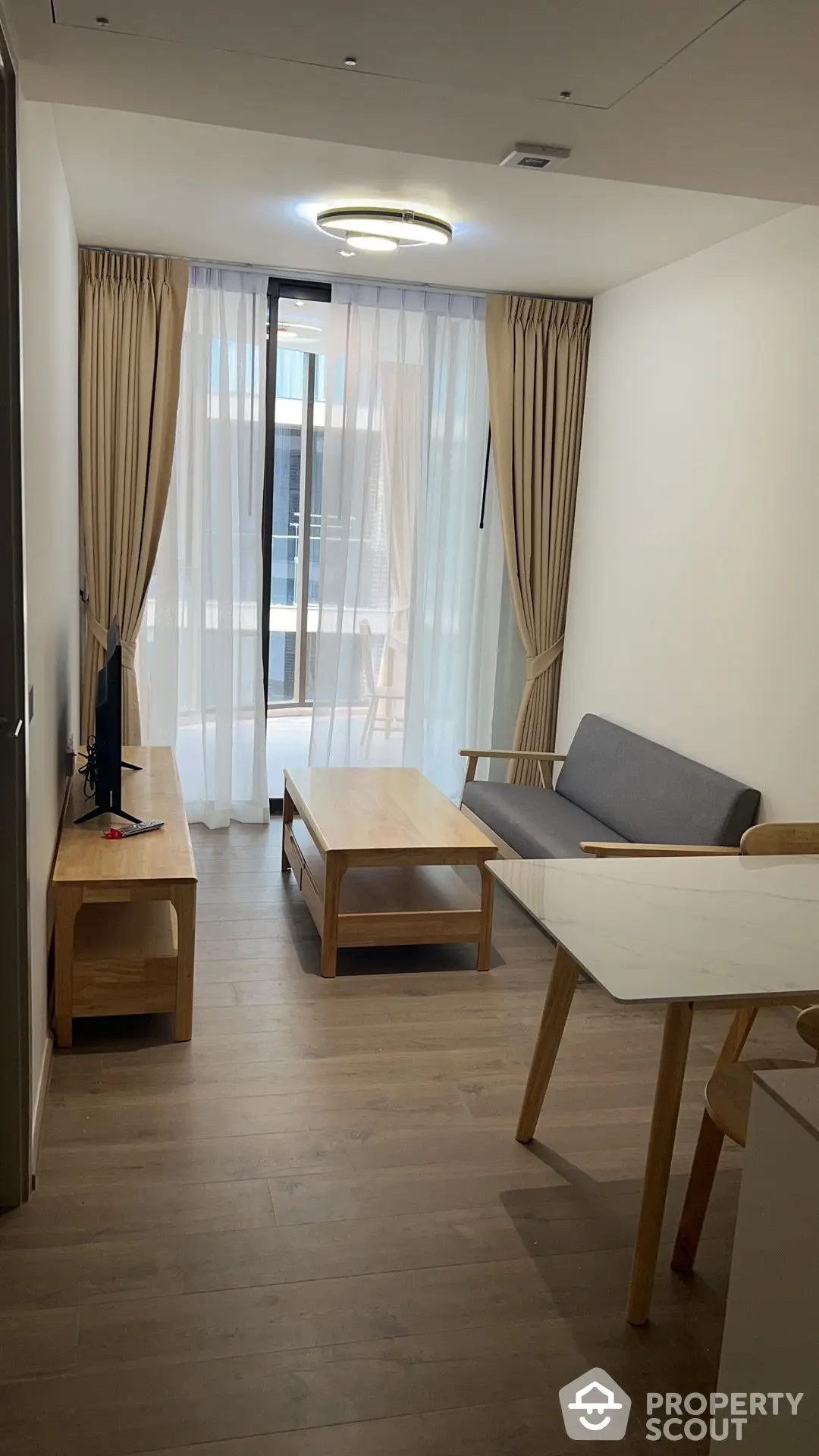 Modern living room with elegant wooden furniture, neutral color palette, and natural light streaming in from the balcony, perfect for urban living.