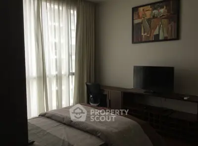 Cozy bedroom with modern decor, featuring a large window and stylish furnishings.