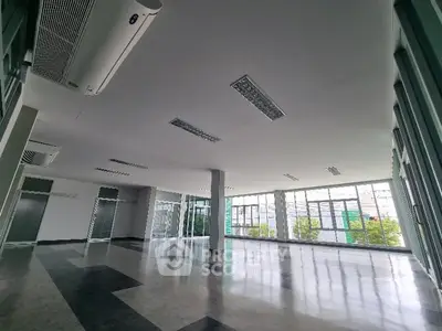 Spacious open-plan interior with large windows and modern lighting, ideal for versatile use.