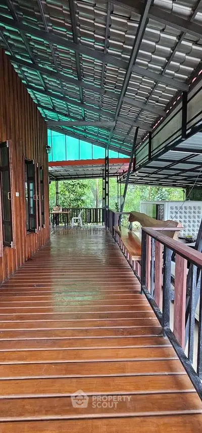 Spacious wooden balcony with metal roof and scenic garden view