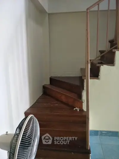 Cozy interior staircase with wooden steps and a fan, perfect for compact living spaces.