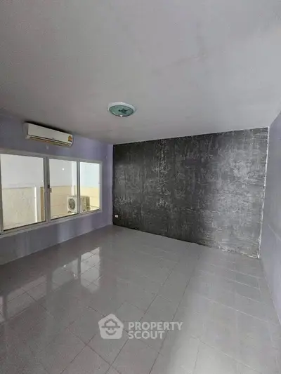 Spacious empty room with large window and air conditioning, ideal for customization.