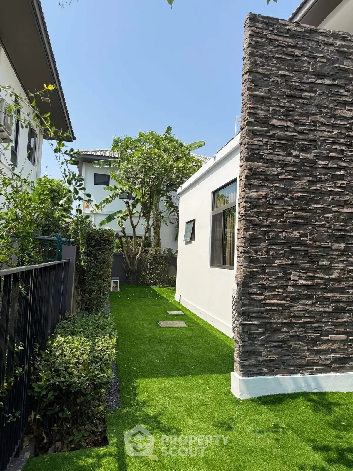 Charming modern home exterior with lush green lawn and stone accent wall, perfect for family living.