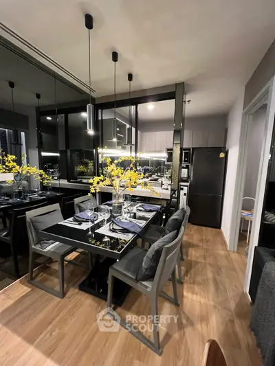 Modern kitchen with sleek black dining table, elegant lighting, and stylish decor in a contemporary apartment.