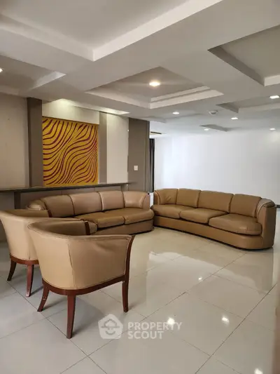 Spacious modern living room with elegant leather sofas and stylish ceiling design.