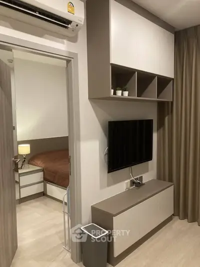 Modern living room with sleek TV setup and cozy bedroom view