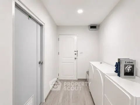 Modern minimalist hallway with sleek white furniture and wooden flooring