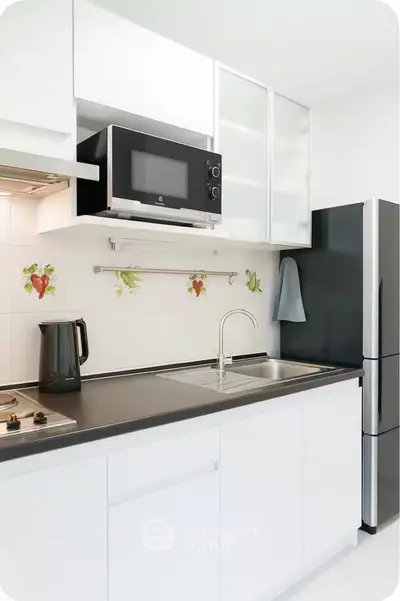 Modern kitchen with sleek black countertop and built-in microwave, featuring a stylish fridge and electric stove.