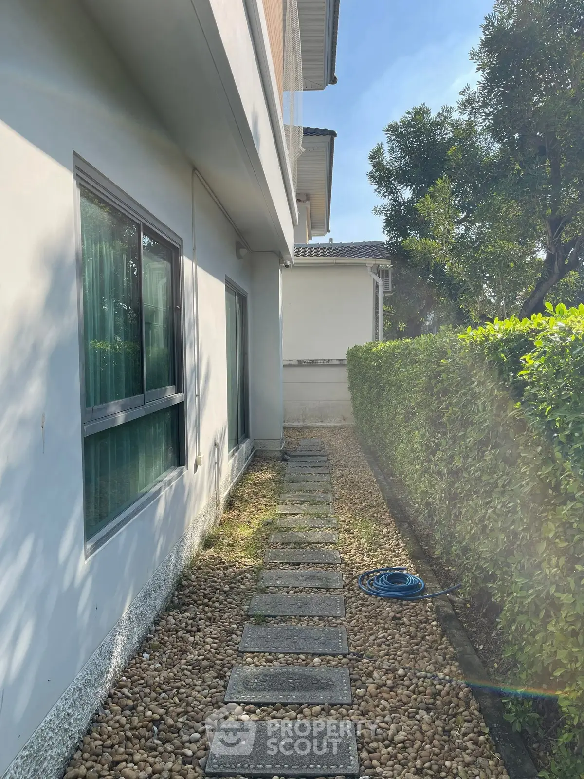 Charming exterior pathway with lush greenery and modern architecture, perfect for serene outdoor living.