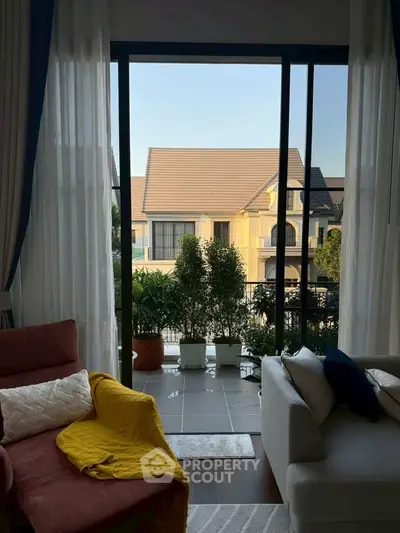 Charming living room with cozy seating and balcony view of elegant houses.