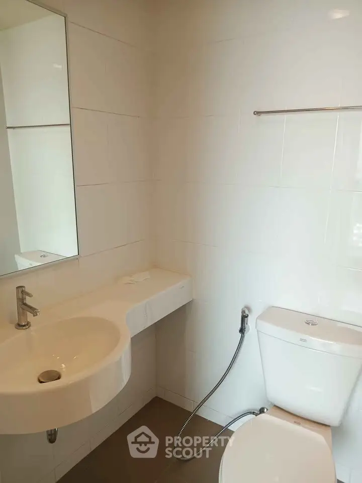Modern bathroom with sleek white fixtures and minimalist design, featuring a wall-mounted sink and toilet.