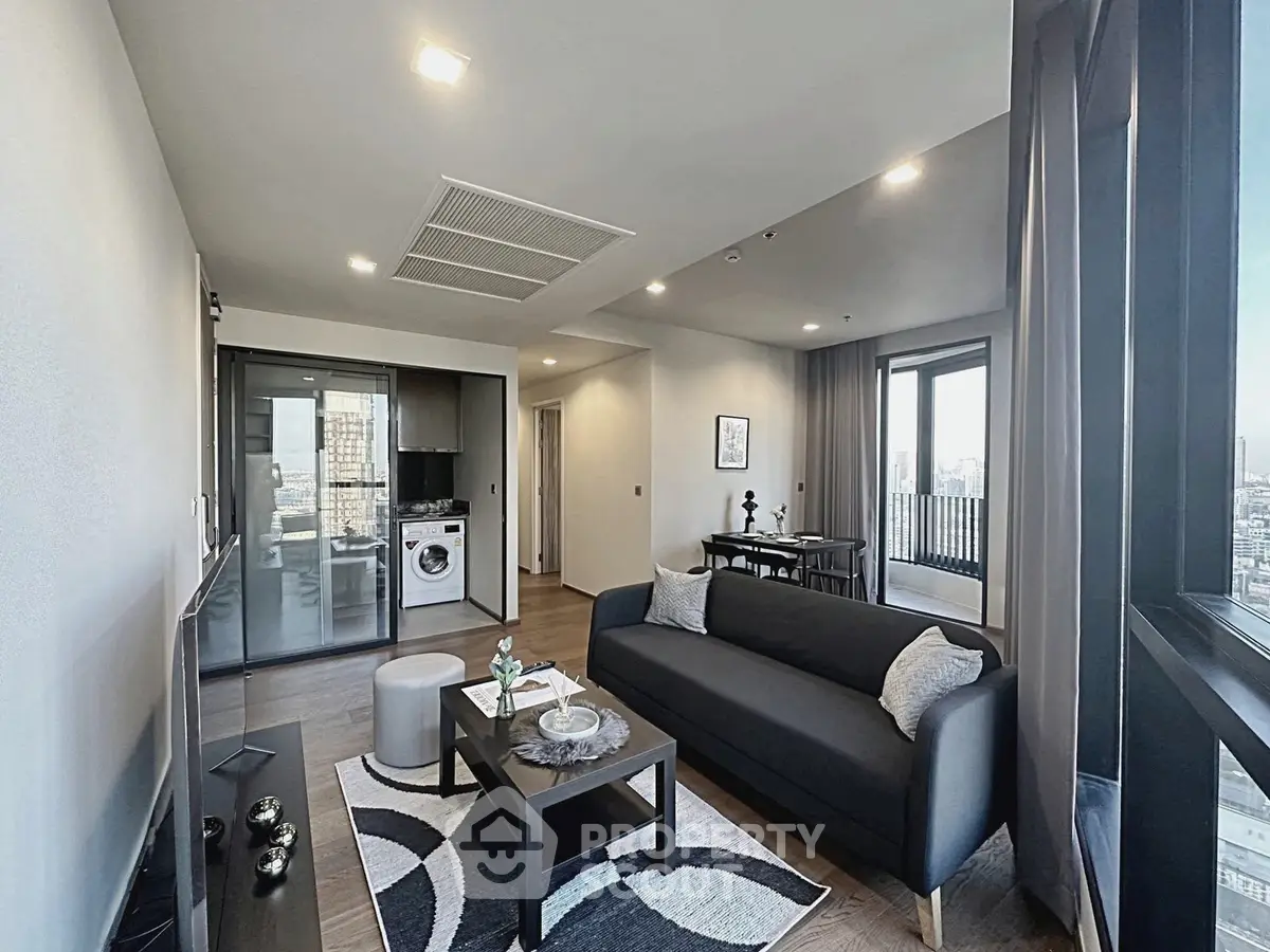 Modern living room with sleek furniture and city view balcony in a stylish apartment.