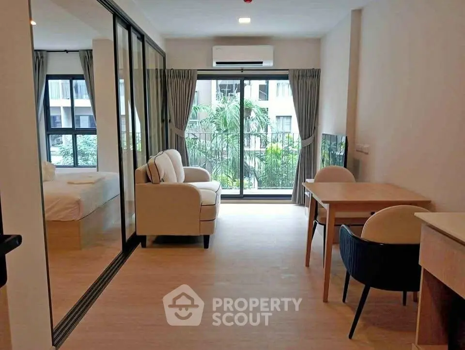 Spacious living room with modern furniture and large windows offering a lush garden view.