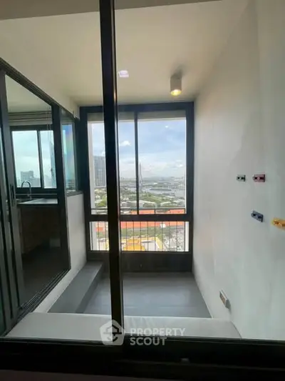 Modern apartment with stunning city view from enclosed balcony, featuring sleek glass doors and minimalist design.