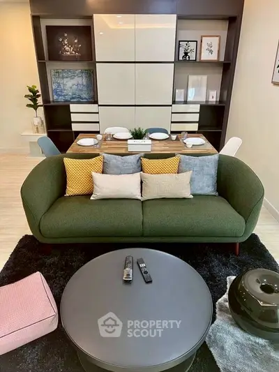 Stylish modern living room with green sofa, elegant dining area, and chic decor accents.