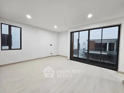 Spacious modern living room with large windows and balcony access in a contemporary home.